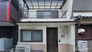 Un edificio con entrada protegida por una reja, unidades de aire acondicionado y una bicicleta estacionada afuera.