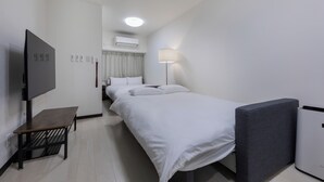 Habitación de hotel con cama, televisor, escritorio, lámpara y aire acondicionado.