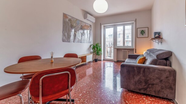 A modern living space with a dining area, a sofa, a large window, and a map on the wall. - Casilina Green House - Metro Malatesta (Rome)