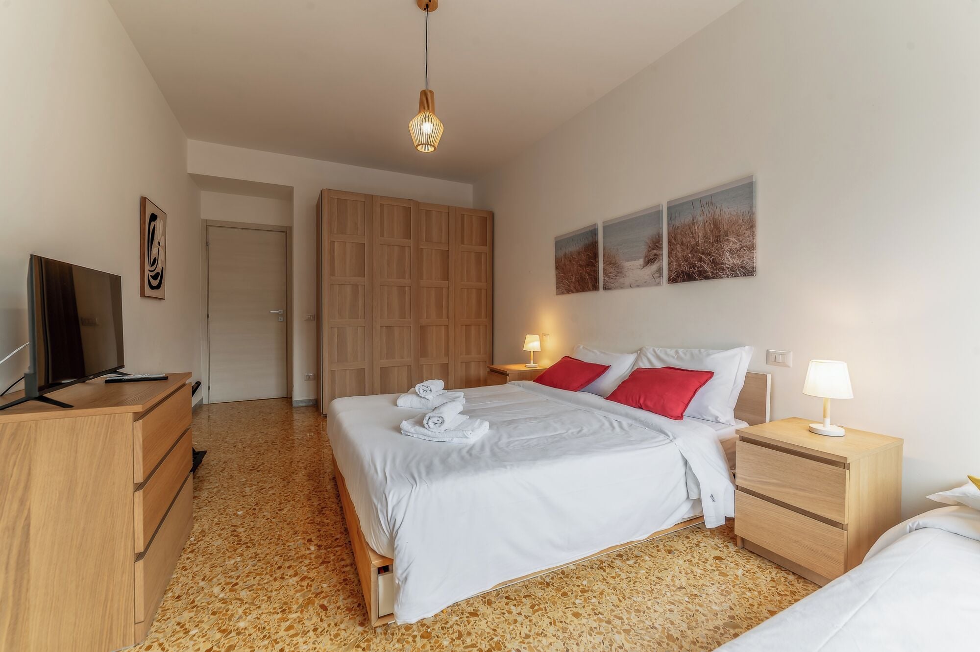 A bedroom with a bed, a TV, a wardrobe, a desk, and a lamp.