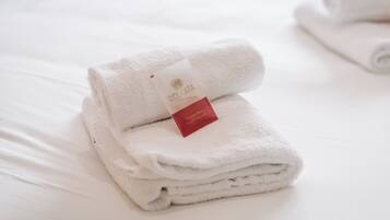 Una toalla blanca doblada con una etiqueta que dice 'DELICATA' y una etiqueta roja más pequeña que indica 'gel de ducha y lavado capilar Dolce'.