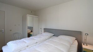 A bedroom with a bed, a wardrobe, a chair, and a desk with a lamp. - Horizon 95 Comfortable villa with boxspring on vacation park (Renesse)