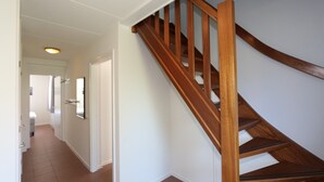 A staircase with wooden handrails and a white wall. - Horizon 95 Comfortable villa with boxspring on vacation park (Renesse)
