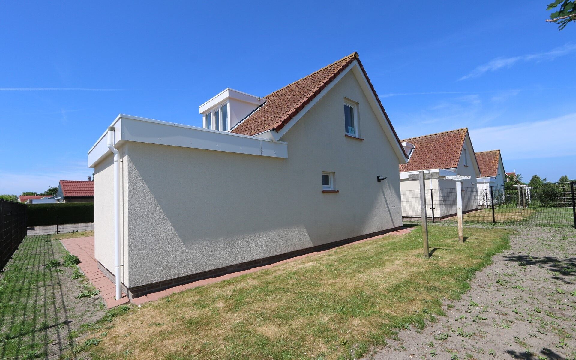 A modern two-story house with a sloped roof, a small window, and a paved driveway.