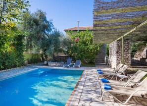 A swimming pool with lounge chairs and a stone wall. - Villa Maistro in Lefkada (Lefkada)