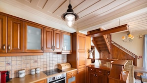 A kitchen with wooden cabinets, a built-in oven, a tiled backsplash, and a wooden staircase. - Villa Pelagos Kyma in Lefkada (Lefkada)