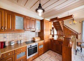 A kitchen with wooden cabinets, a built-in oven, a tiled backsplash, and a wooden staircase. - Villa Pelagos Kyma in Lefkada (Lefkada)