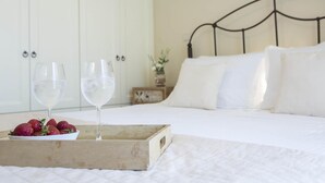 A neatly made bed with white linens, a wooden tray with strawberries and two glasses of water, and a white wardrobe in the background. - Villa Melanthi in Lefkada (Lefkada)