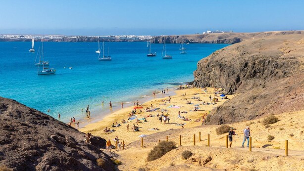 A beach with clear blue water, sandy shore, and rocky cliffs. - Villa Yaiza Secret 1 (Yaiza)