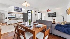 A modern kitchen with white cabinets, a dining table set for four, and a sofa in the living area. - Villa Paula in Costa Teguise (Teguise)