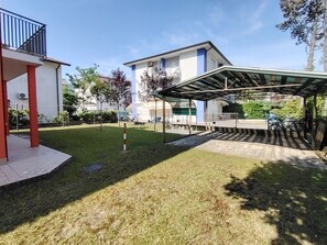 Un quartier résidentiel doté d’un patio couvert, d’une pelouse et d’un immeuble avec balcon.