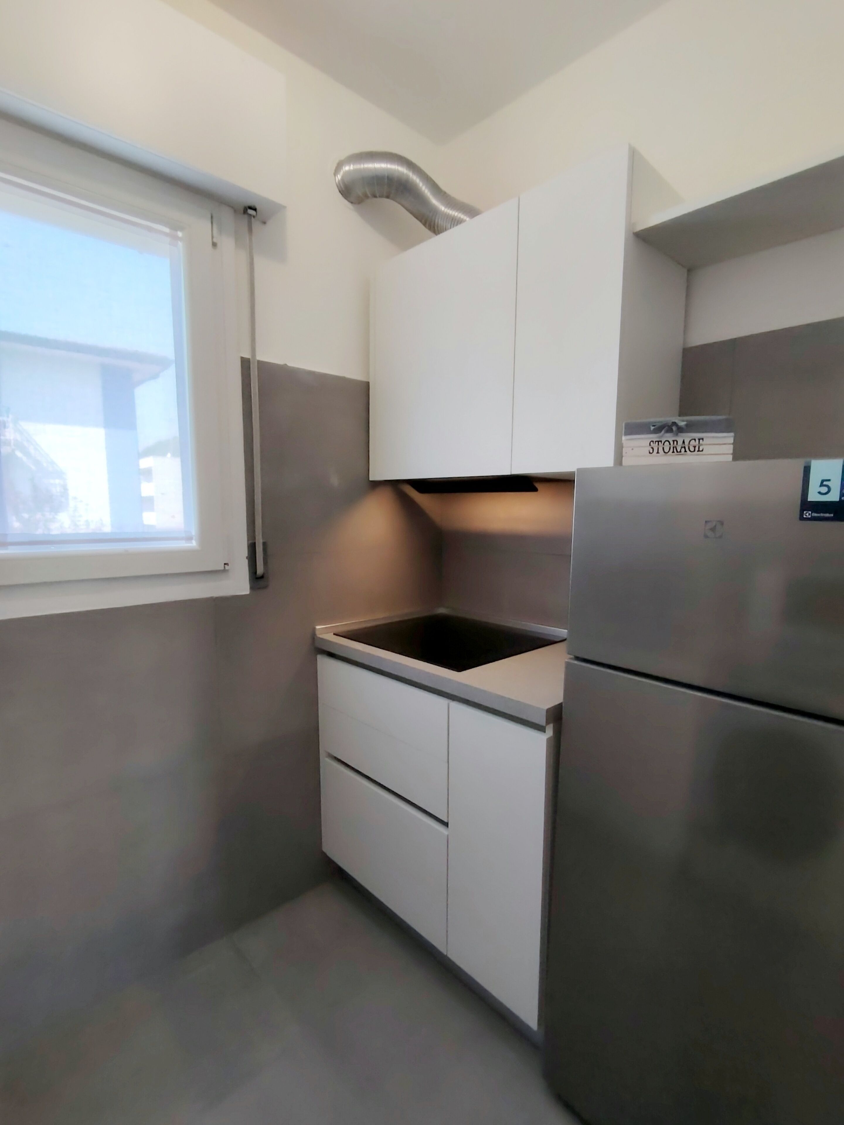 Une cuisine compacte équipée d’une cuisinière intégrée, d’un réfrigérateur et d’un meuble de rangement.