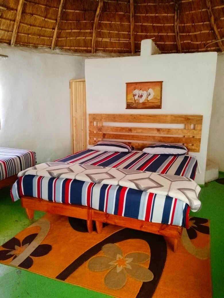 Ein Zimmer mit einem Bett, einem Holz-Kopfteil, einem Gemälde und einem grünen Teppich.