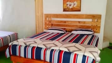 A room with a bed, a wooden headboard, a painting, and a green carpet.