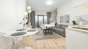 A modern, well-lit room with a dining table, chairs, a sofa, a bed, and a kitchen area. - MARGI Milky Apartament (Szczecin)