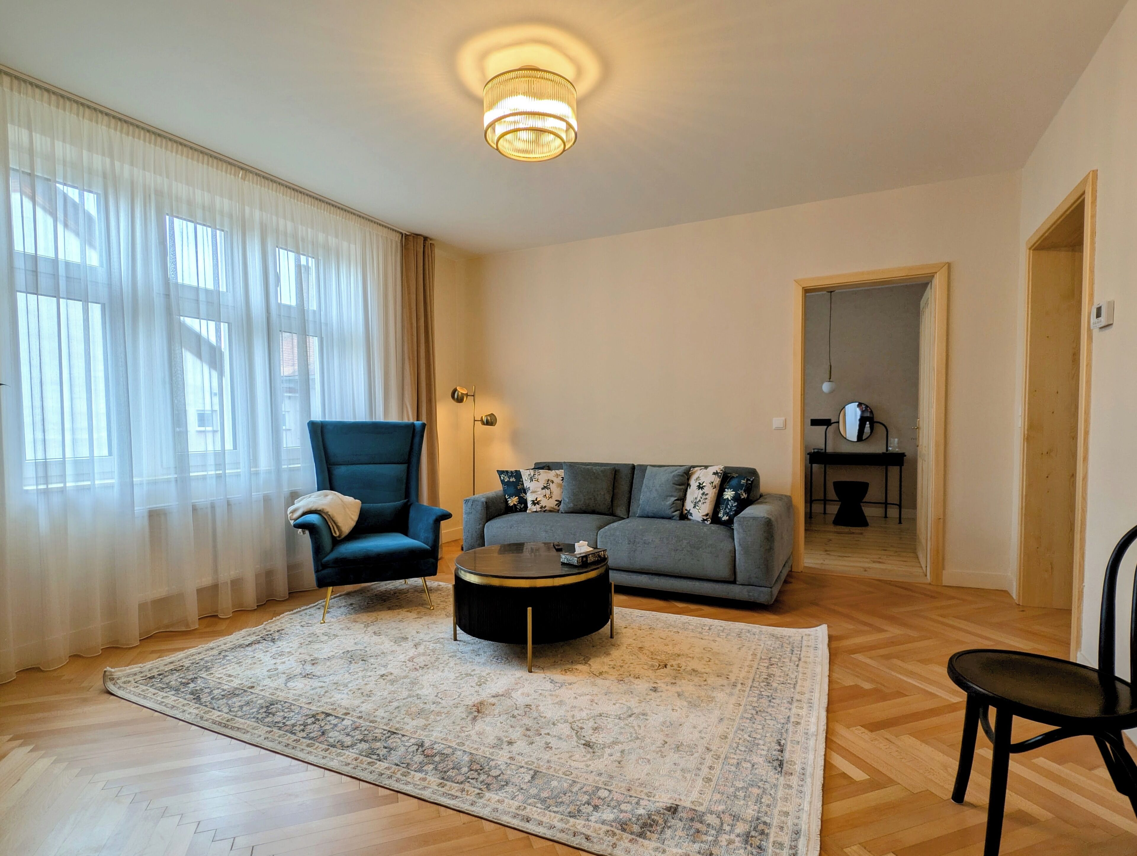 Una sala de estar con sofá, sillón, mesa de centro y alfombra.