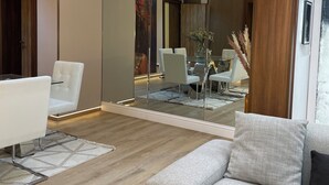 A modern living room with a sofa, a dining table, and chairs. There is a glass partition and a wooden ceiling. - Goldvika  (Abuja)
