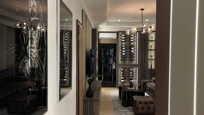 A modern interior with a wooden floor, a central seating area, a wine rack, and a large mirror. - Goldvika  (Abuja)