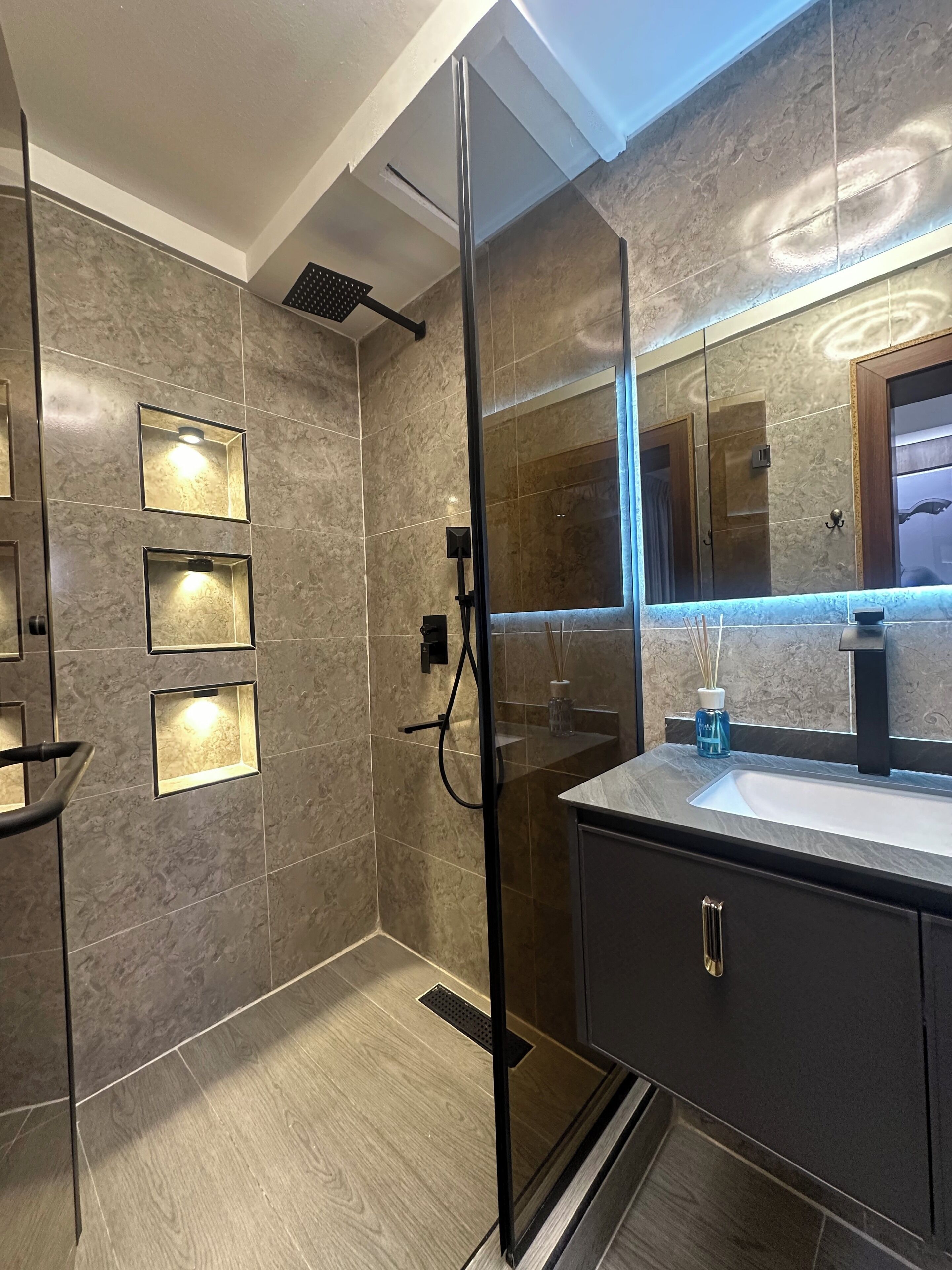 Une salle de bain moderne avec une douche à parois de verre, un meuble-lavabo et un grand miroir.