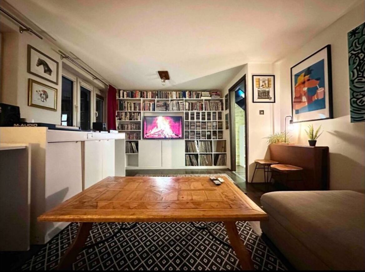 A living room with a wooden coffee table, a sofa, a bookshelf, and a television.