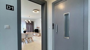 Een modern interieur met een grijze deur, een eethoek met een tafel en stoelen, en een keuken op de achtergrond.