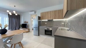 Een moderne keuken met een ingebouwde oven, een roestvrijstalen koelkast en een grijs aanrecht.