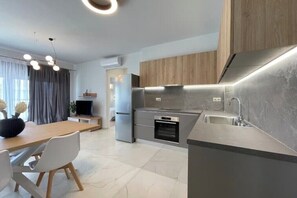 A modern kitchen with a built-in oven, a stainless steel refrigerator, and a grey countertop. - Athenean Oasis In Ellinikon-D1 (Elliniko)