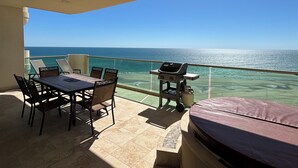 A balcony with a table and chairs, a grill, and a view of the ocean. - Tessoro 704 - Amazing beachy ocean front condo (Puerto Peñasco)