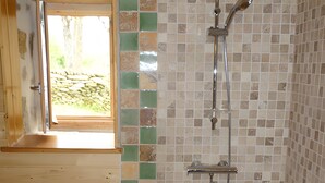 Une douche avec un mur carrelé, un plafond en bois et une fenêtre.