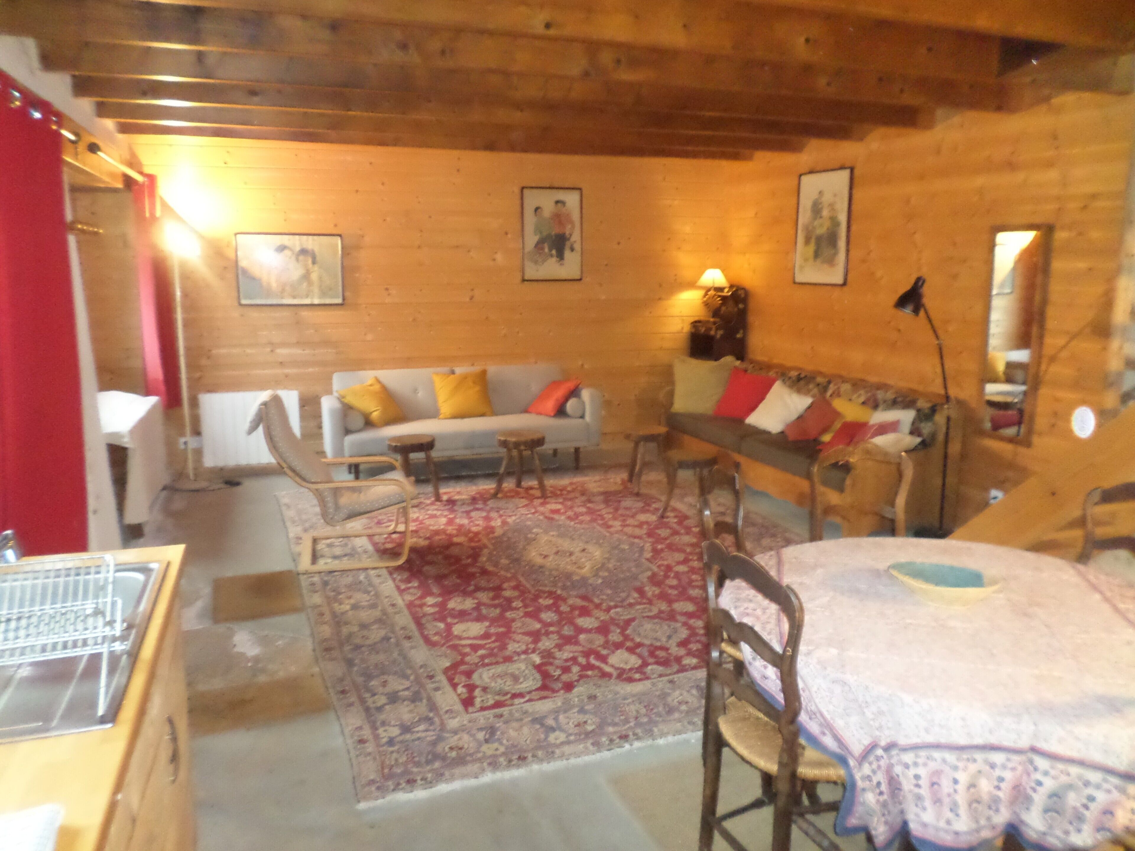 Un intérieur en bois comprenant un canapé, des fauteuils, une table et un tapis à motifs.