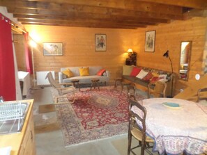 Un intérieur en bois comprenant un canapé, des fauteuils, une table et un tapis à motifs.