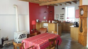 Ein Essbereich mit rot-weiß gestreiftem Tischläufer, Holzhöhlen, einem weißen Herd, einer roten Wand und einer Küche im Hintergrund.