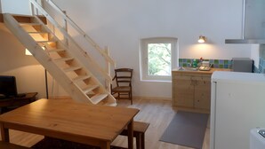 Une cuisine avec un escalier en bois, une table à manger et une fenêtre.