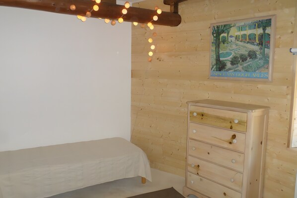 Une pièce de style cabane en bois, avec un lit, une commode et un tableau accroché au mur.
