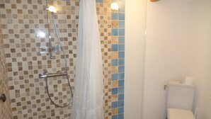 Une salle de bain avec douche, toilettes et murs carrelés.