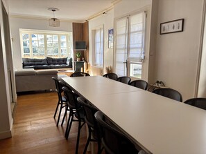 Un espace repas comprenant une longue table, des chaises, un canapé et un téléviseur.