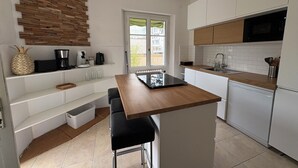 Et moderne køkken med hvide skabe, en træbordplade, en indbygget komfur og et vindue med udsigt.