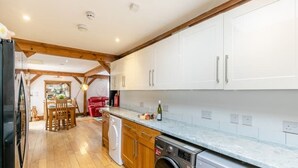 A kitchen with wooden cabinets, a washing machine, and a dining area with a table and chairs.