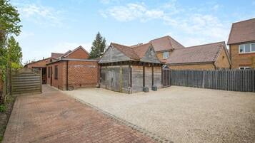 A residential area with brick houses, a gravel driveway, and a wooden fence.