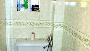 Ein Badezimmer mit Toilette, Toilettenpapier und einem Händetrockner.