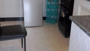 Eine Küche mit Kühlschrank, Spüle, Herd und einem Stuhl.