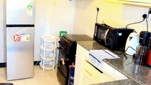 Eine kleine Küche mit Kühlschrank, Mikrowelle, Herd und einer Arbeitsplatte.