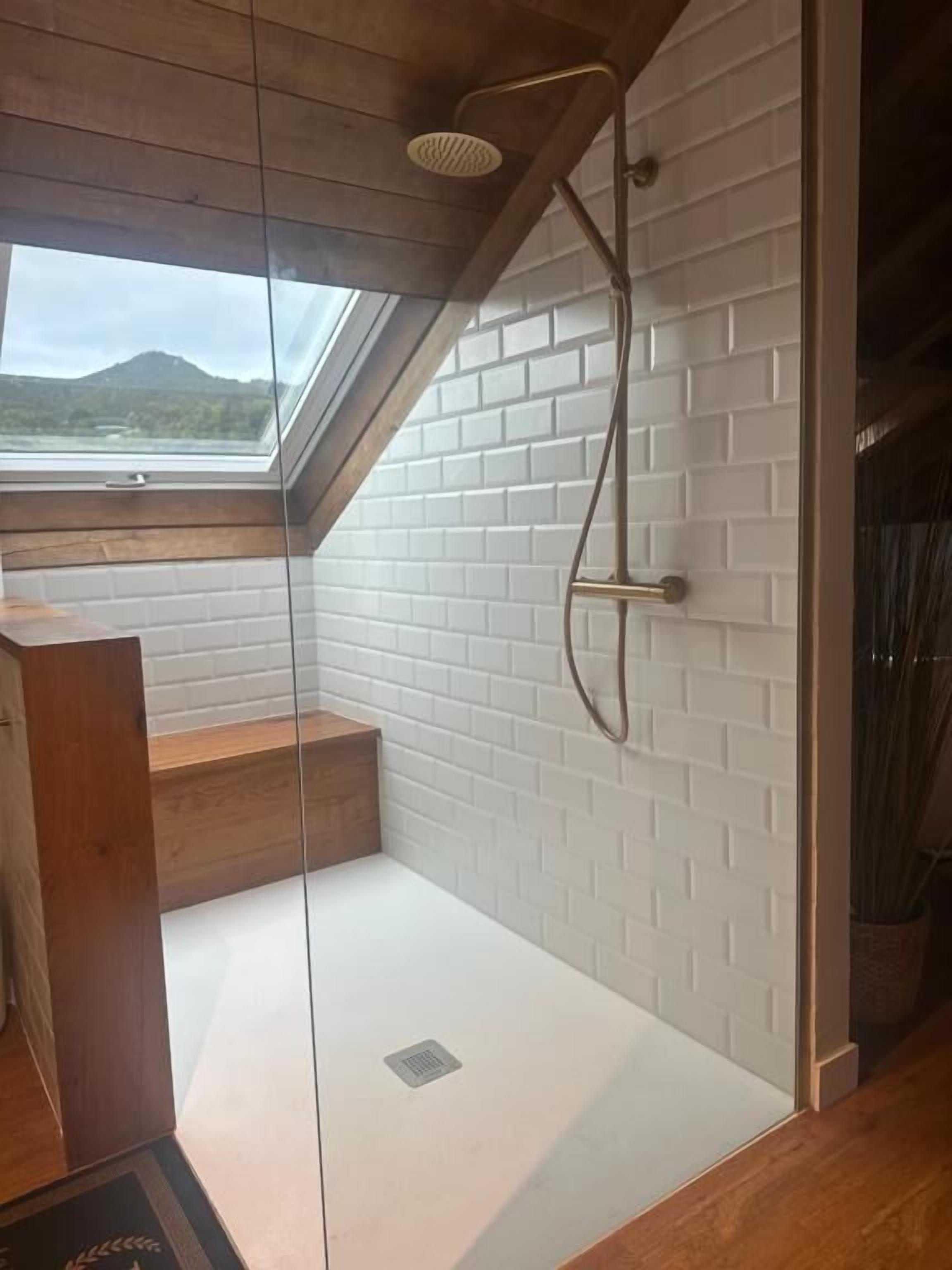 Eine moderne Dusche mit Glastür, Oberlicht und Bergblick.