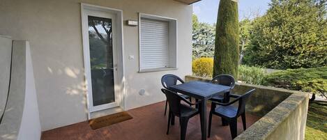 A patio with a table and chairs, a door with a window, and a welcome mat.