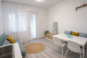 Une pièce moderne et bien éclairée, avec un canapé, une table à manger et une petite plante.