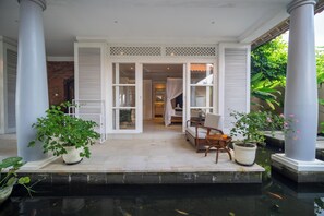 Un espace extérieur abrité, aménagé avec des sièges, un élément décoratif aquatique et offrant une vue sur l’intérieur du bâtiment.