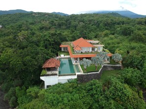 Un'ampia casa con piscina, immersa in una fitta foresta e colline.
