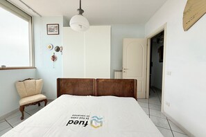 A bedroom with a bed, a chair, a wardrobe, a door, and a window. -  P087 - Porto Recanati, exclusive penthouse with panoramic terrace (Porto Recanati)
