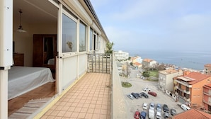 A balcony with a view of the sea, a tiled floor, a bed, and a door leading to a room. -  P087 - Porto Recanati, exclusive penthouse with panoramic terrace (Porto Recanati)