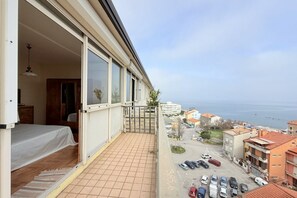 A balcony with a view of the sea, a tiled floor, a bed, and a door leading to a room. -  P087 - Porto Recanati, exclusive penthouse with panoramic terrace (Porto Recanati)
